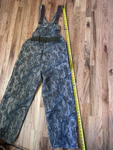 Load image into Gallery viewer, Carhartt Mossy oak tree stand hunting camo vintage overalls men’s size Large/Medium made in USA camo hunting bibs 80s 90s